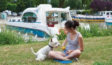 Sediace dievča so psíkom pred zakotvenou loďkou
